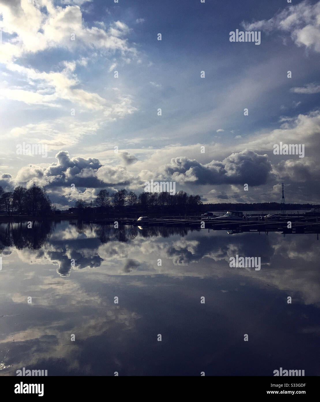 el cielo y las nubes se reflejan en el agua, fondo azul Foto de stock