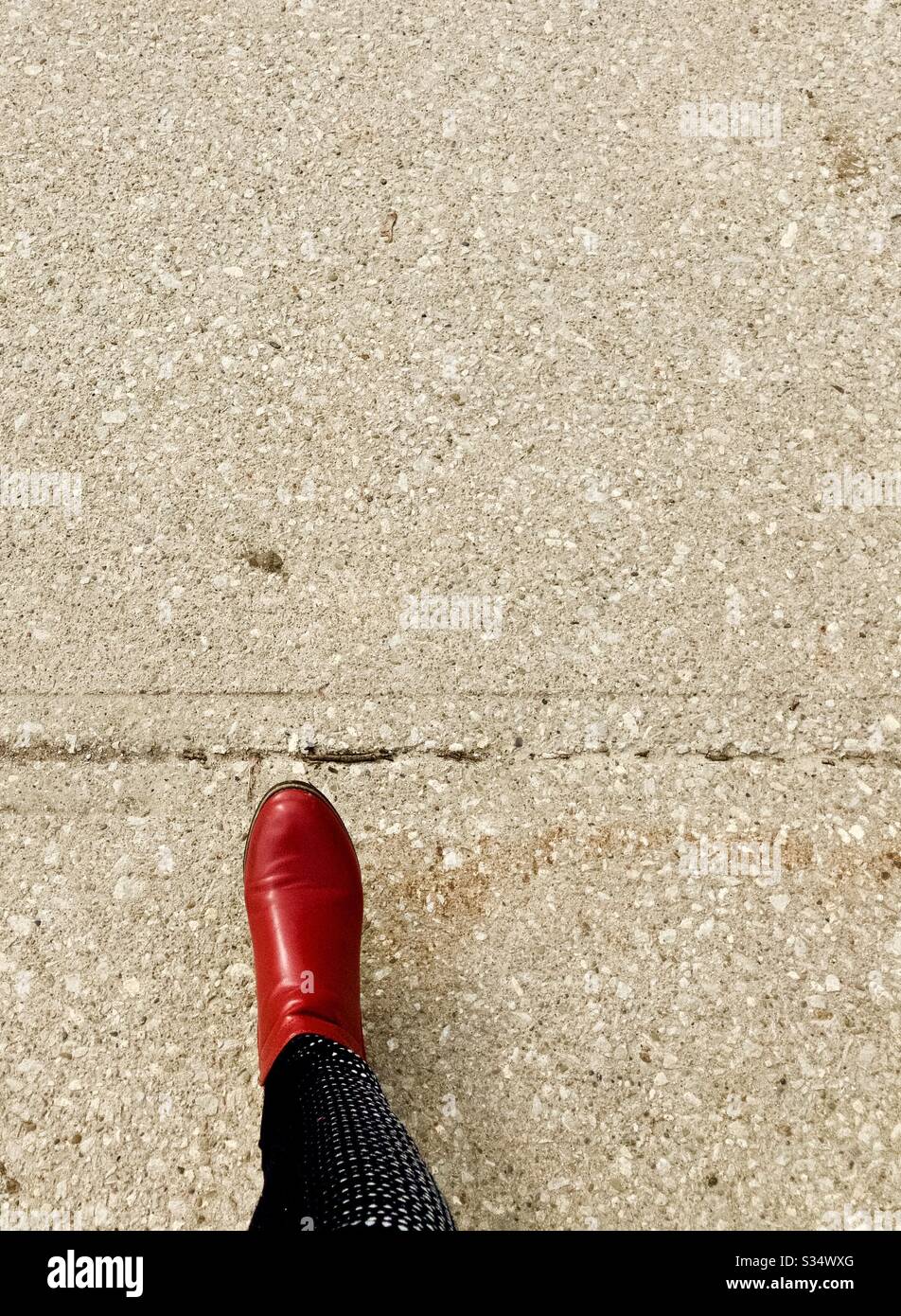 Bota de tobillo roja en el pavimento de hormigón Foto de stock