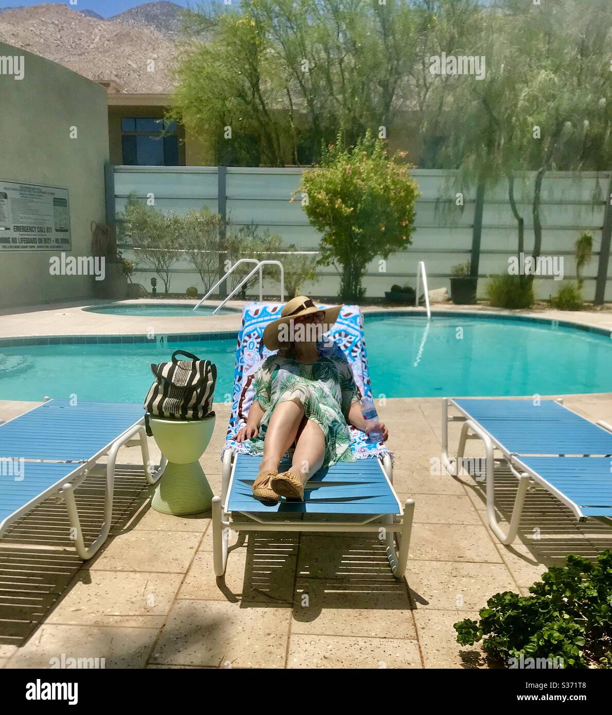 ¡correo de caracol solamente! Mujer se relaja junto a la piscina en Palm Springs CA Agosto 2019 Foto de stock