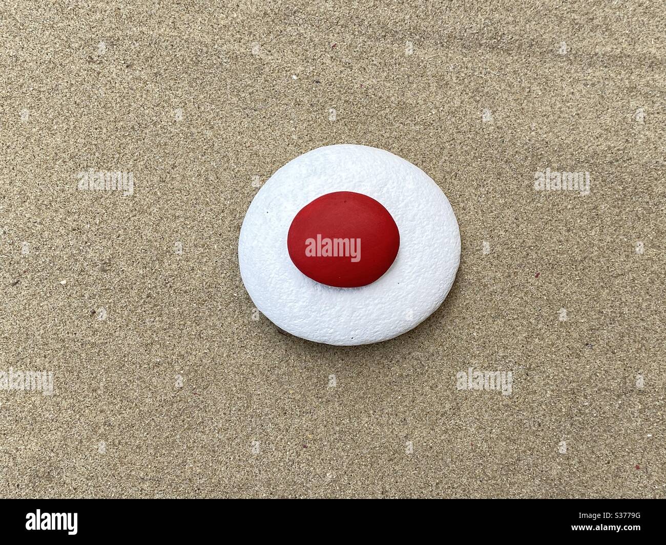 Piedras blancas y rojas, bandera japonesa conceptual en la arena Foto de stock