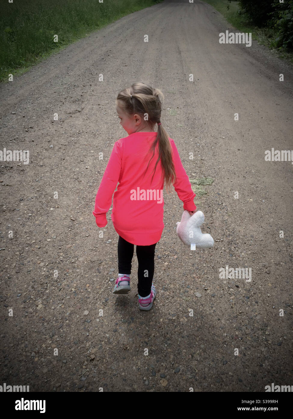 Niño caminando con un animal de peluche; niña y su juguete Foto de stock