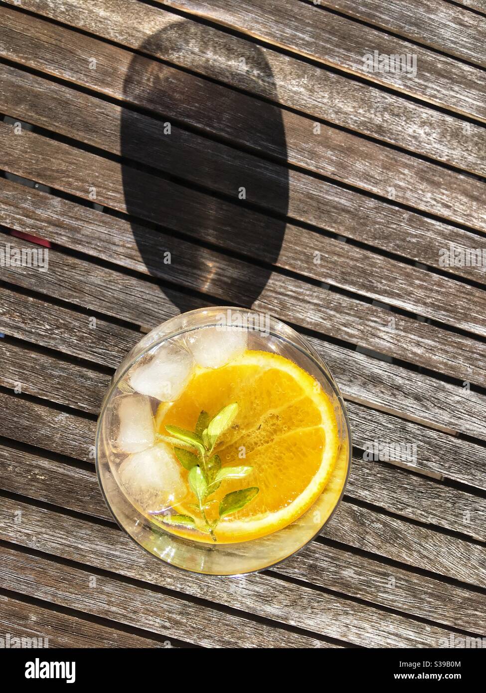 Gin & tonic beber con una rebanada de naranja y.. ramita de orégano Foto de stock