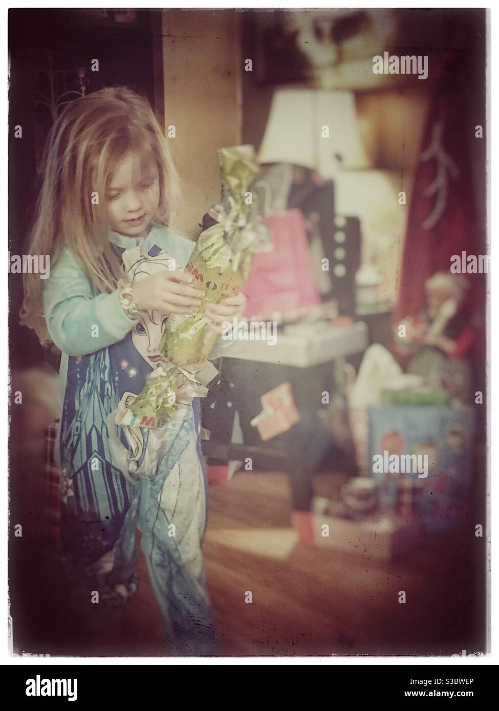 Niña que lleva pijama de Elsa congelado abriendo un regalo de Navidad Foto de stock