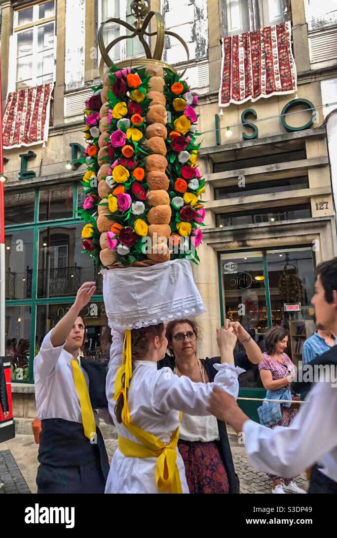 La gente ayuda a un porteador de Tabuleiros a ajustar su Tabuleiro (bandeja) durante la Festa dos Tabuleiros en Tomar, Portugal 2019 Foto de stock