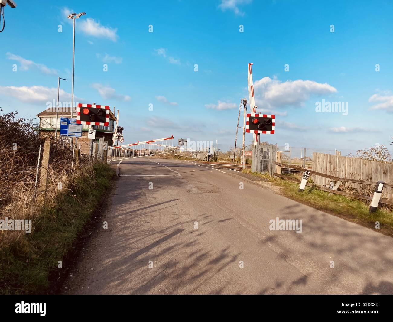 Puerta de cruce de nivel que cierra en una carretera de campo, Reino Unido Foto de stock
