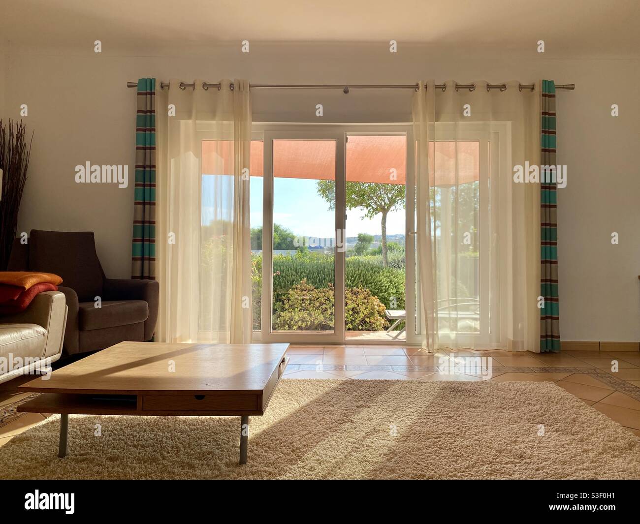 Sala de estar contemporánea con filtro de luz solar a través de vidrio  deslizante puertas Fotografía de stock - Alamy