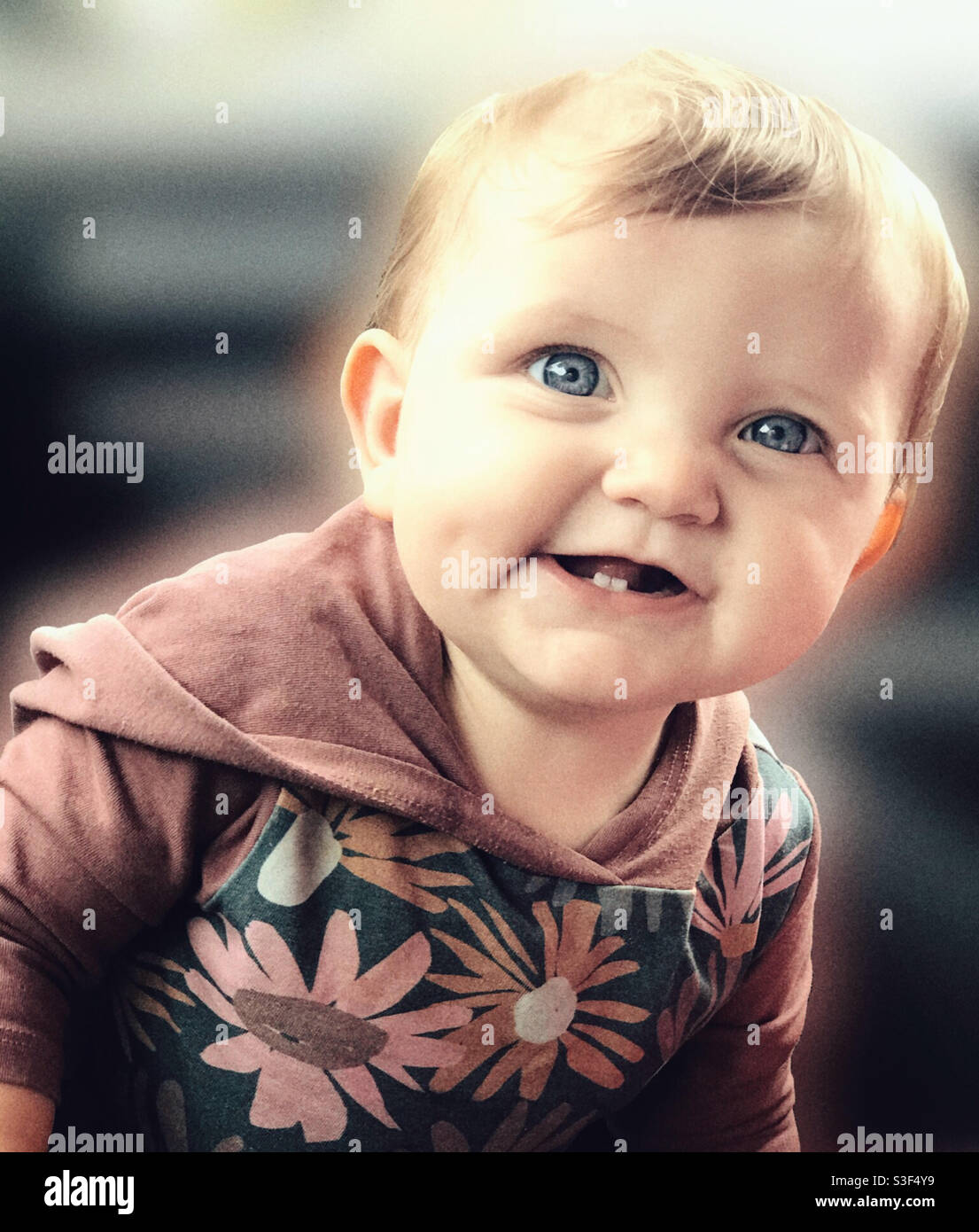 Retrato en color de un bebé de 9 meses que se está ordeñando con Sus dos dientes inferiores se muestran Foto de stock