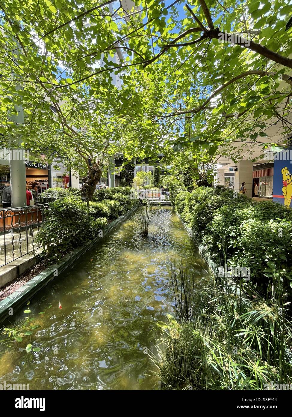 Pequeño arroyo o estanque con árboles en un centro comercial a cielo abierto en el sur de Francia Foto de stock