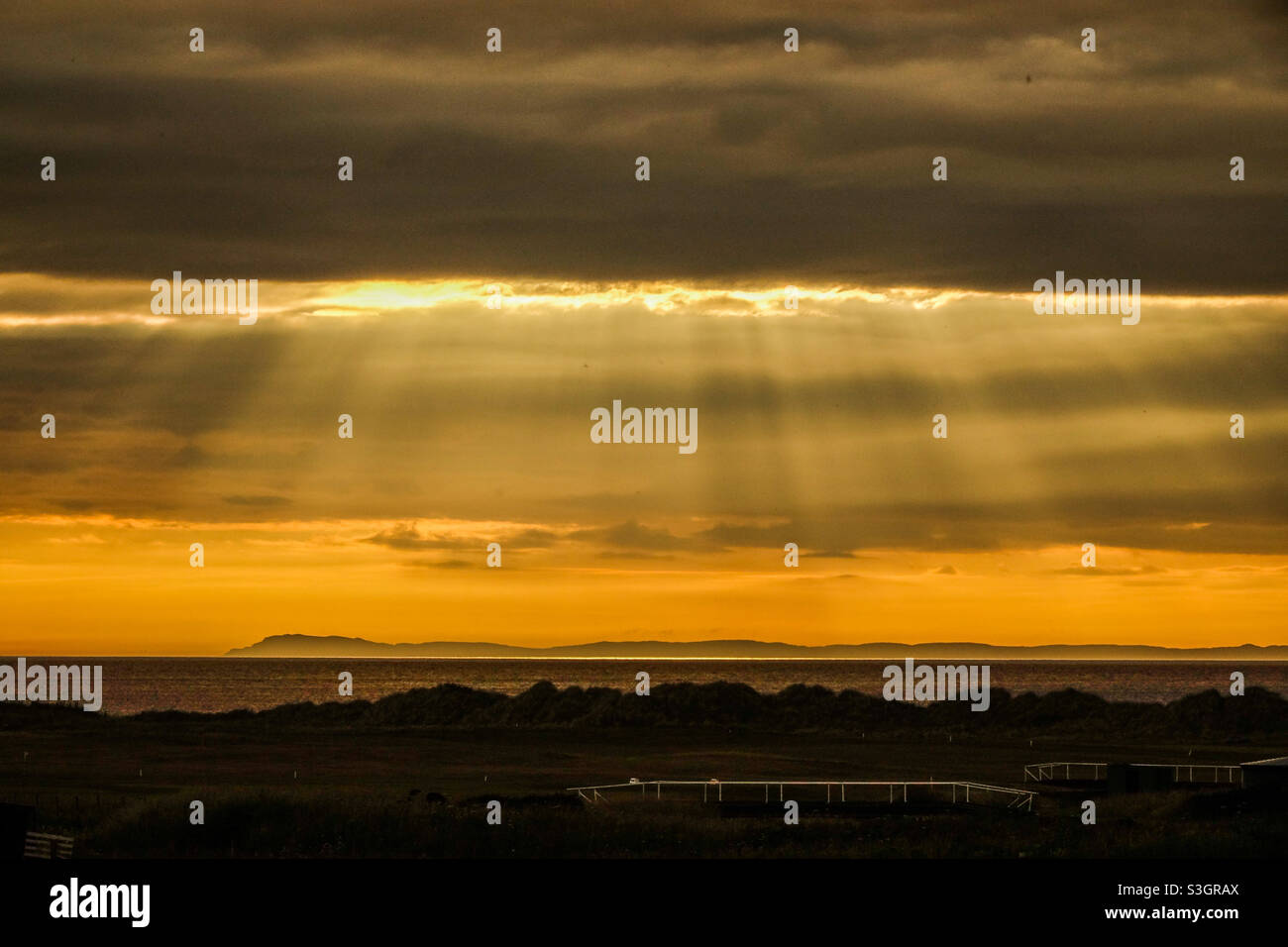 Puesta de sol sobre Islay desde Machrihanish en la península de Kintyre en Escocia Foto de stock