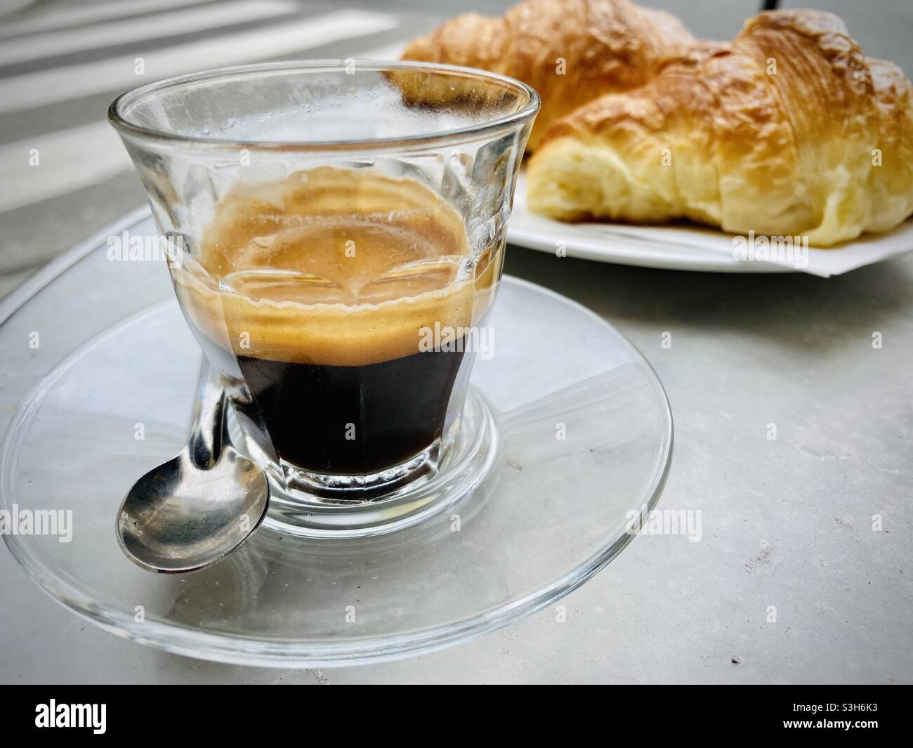 Por la mañana, en un café de París, se sirve una taza caliente de espresso con cruasanes recién hechos Foto de stock