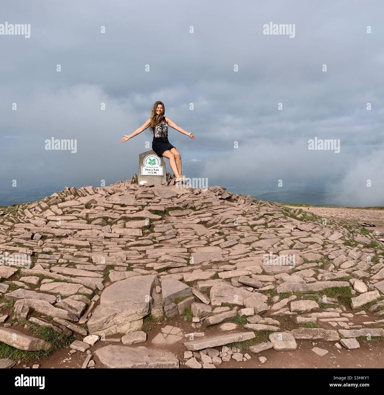 Mujer sentada en la cima de la montaña PEN y FAN en South Wales Brecon Beacons Foto de stock