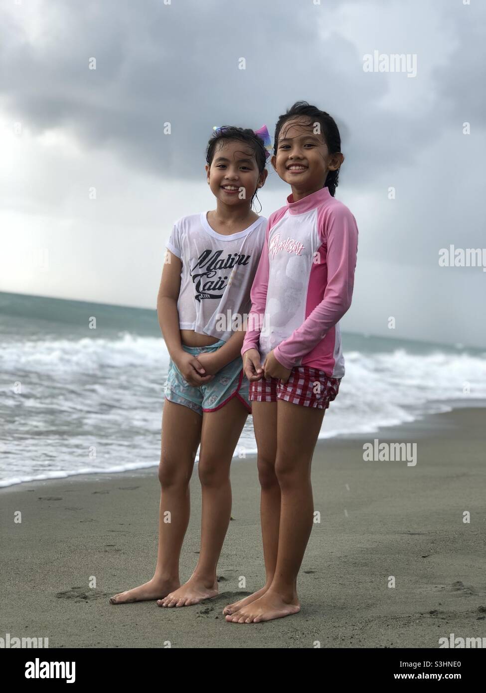 Felices primos en la playa con sus caras sonrientes Foto de stock