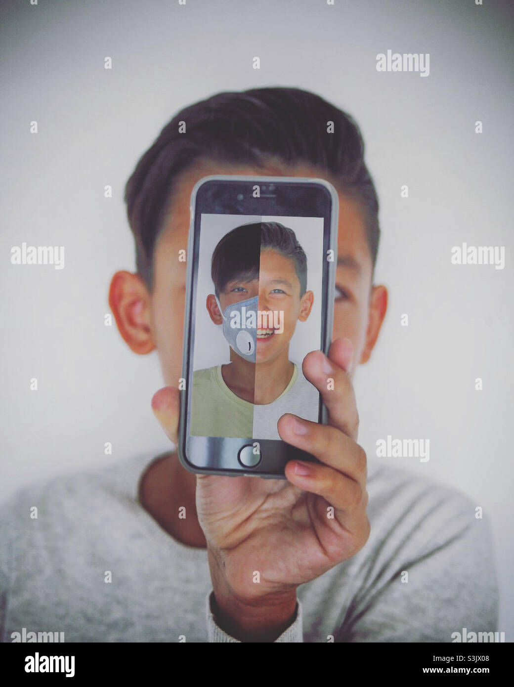 chico joven mostrando la pantalla de su smartohone a la cámara con un retrato si él mismo Foto de stock