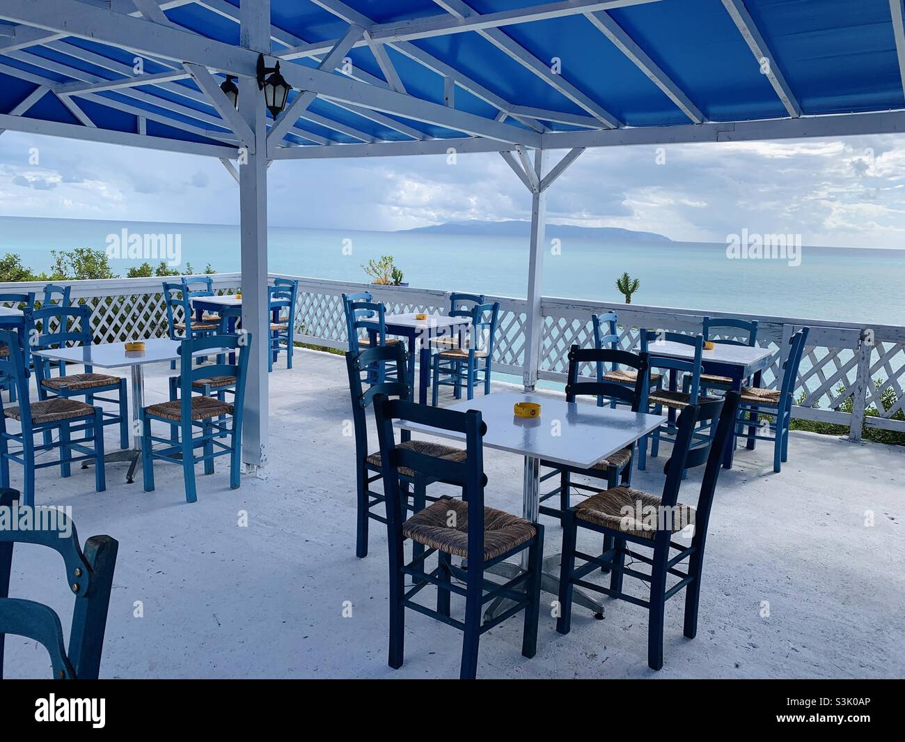 Restaurante vacío en Grecia con bandera azul y blanca en la costa de kefalonia Foto de stock