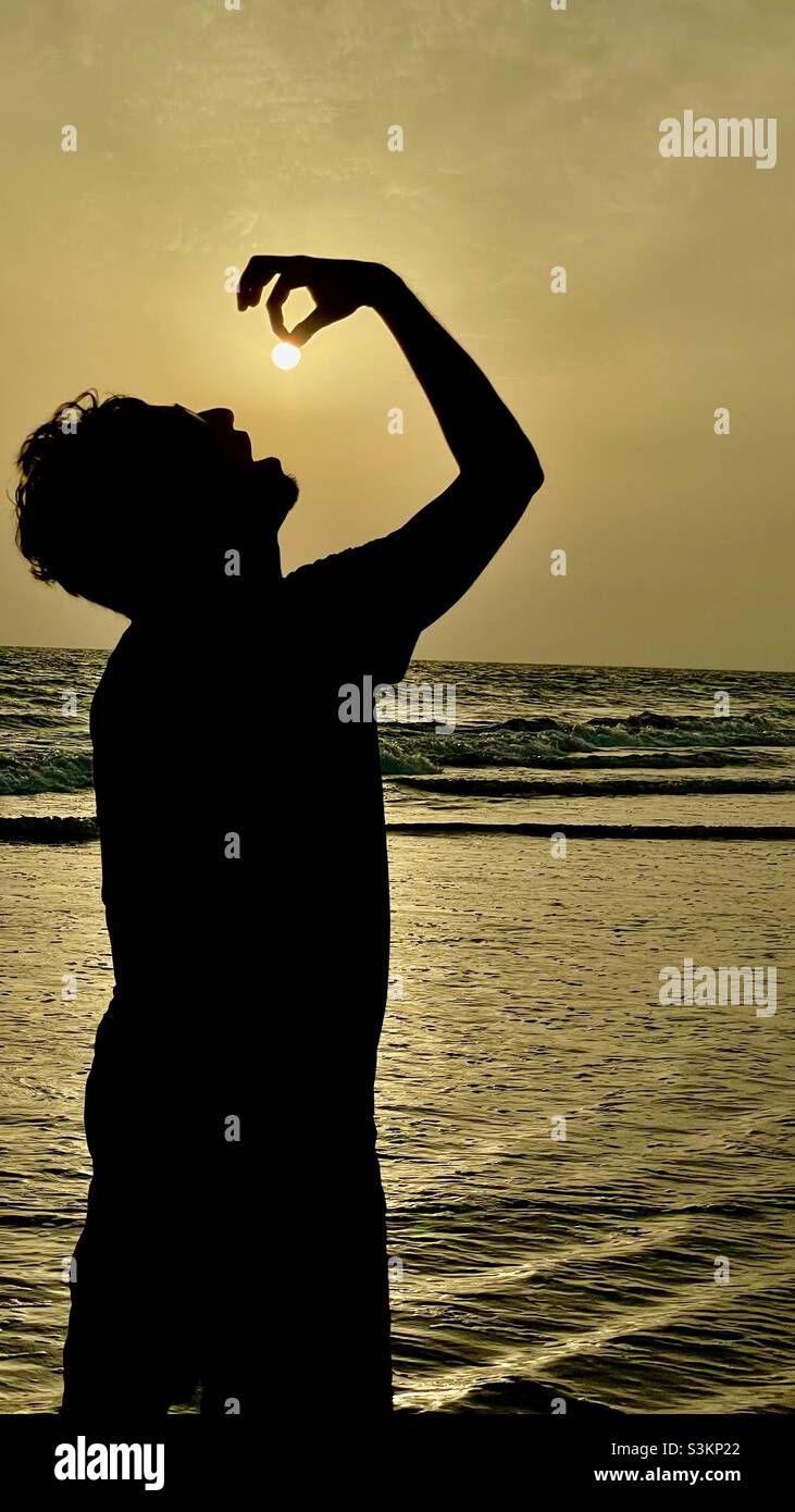 Fotografía de perspectiva , el hombre comiendo el sol Foto de stock