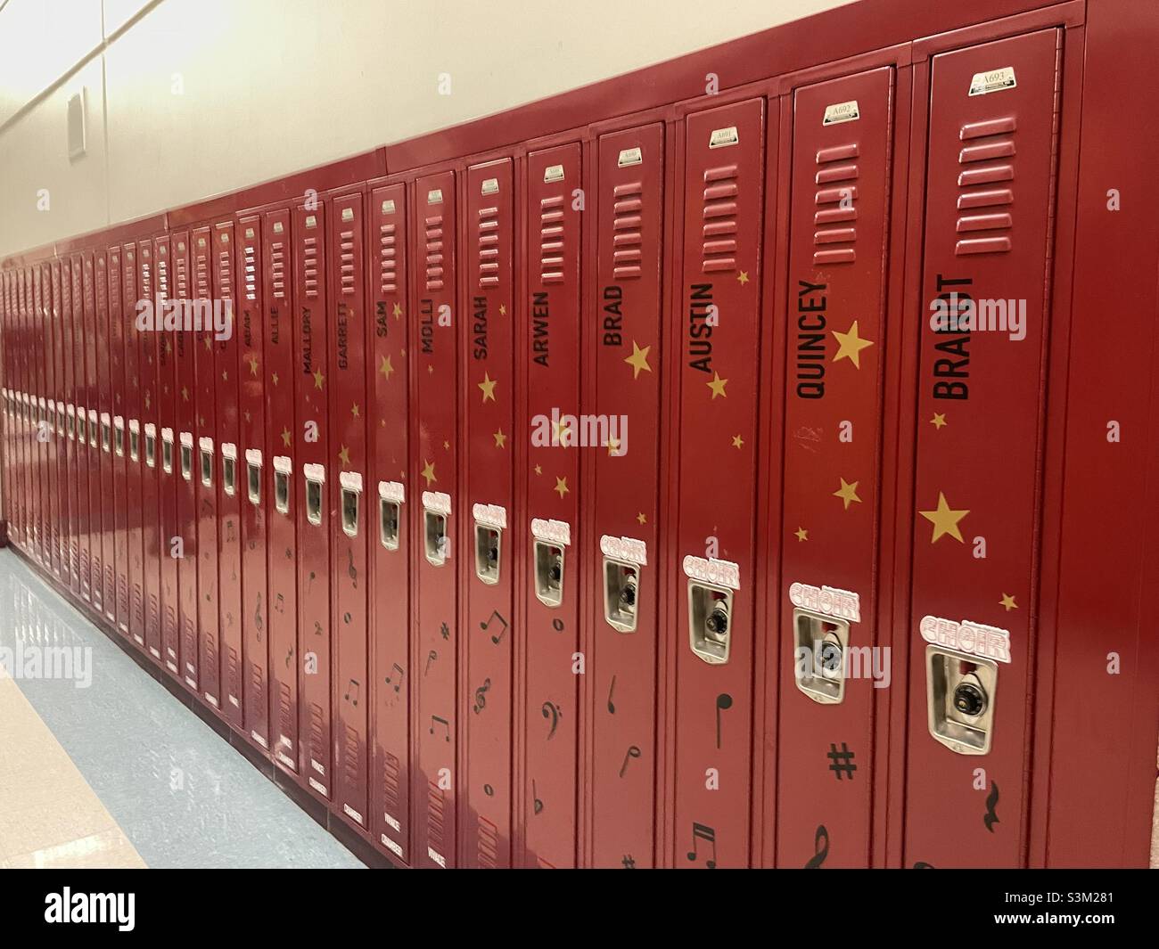 Mirando hacia abajo un pasillo de la escuela secundaria con armarios rojos. Aparentemente, estos casilleros pertenecen a los miembros del coro estudiantil, cada uno nombrado para el estudiante miembro. Foto de stock