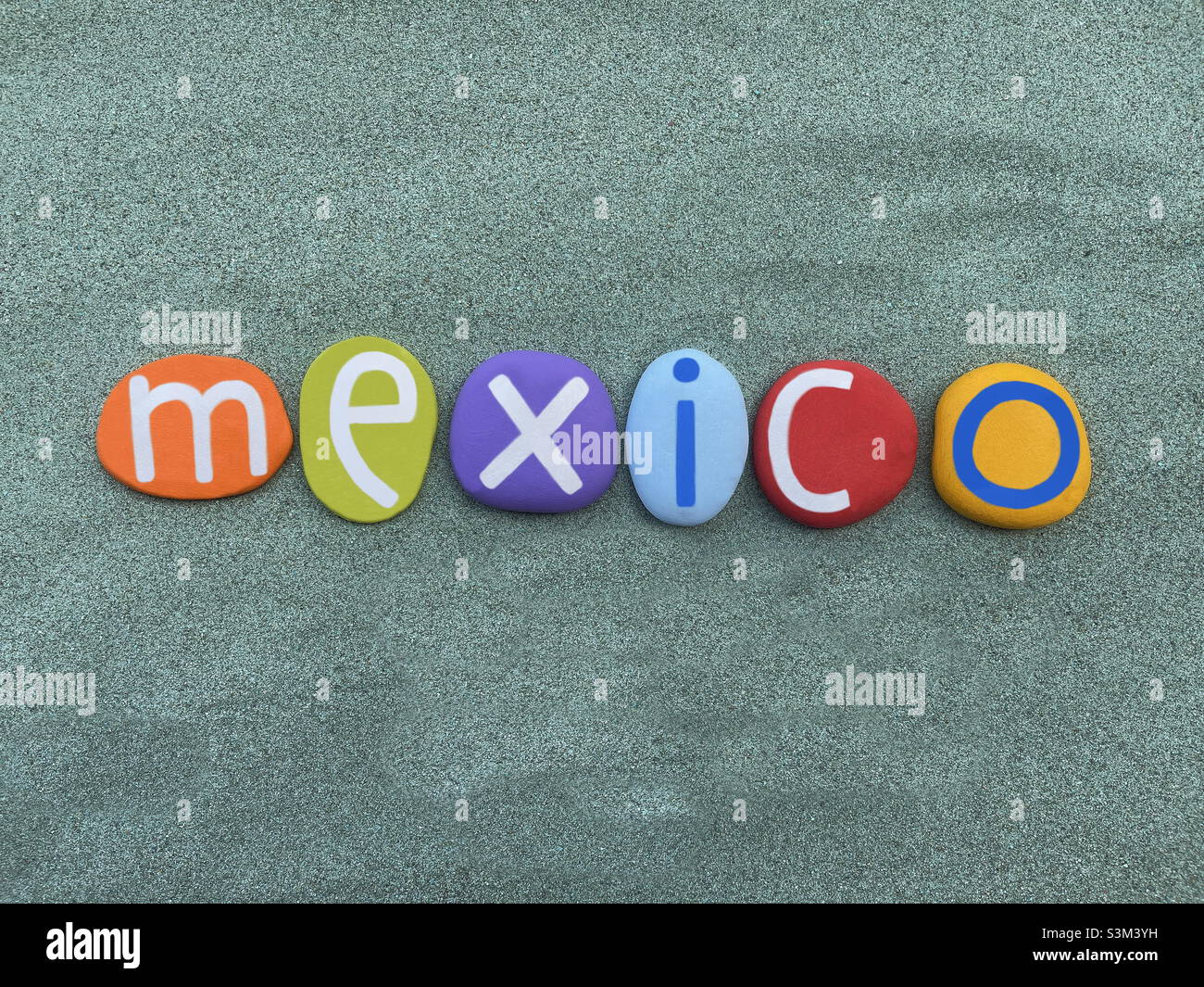 México, recuerdo compuesto por letras de piedra multicolor sobre arena verde Foto de stock