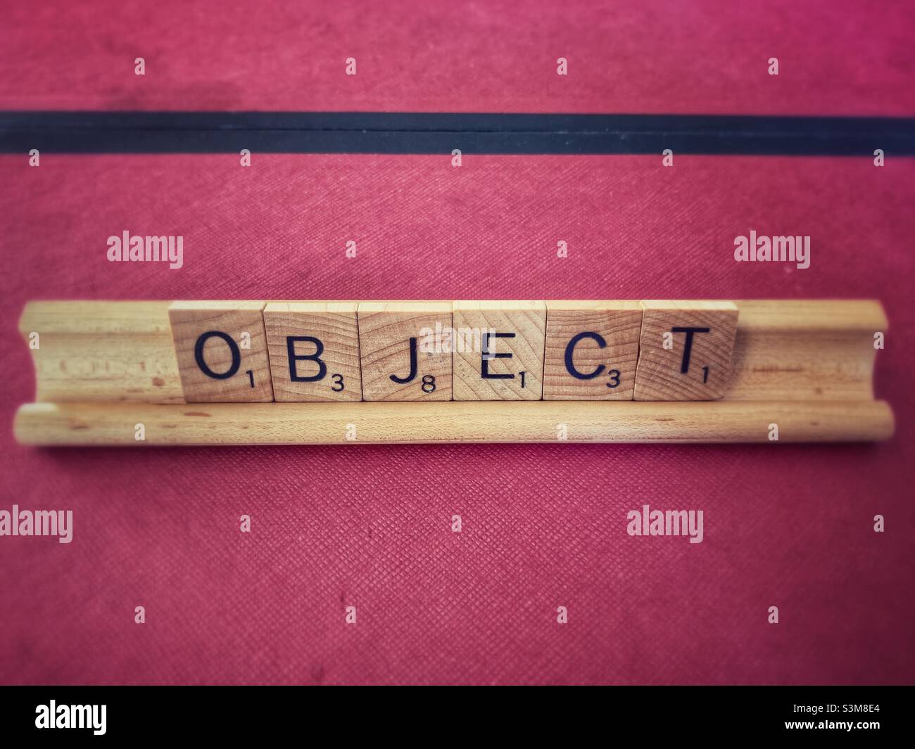 Objeto Scrabble letters, contra fondo de color rosa oscuro. Foto de stock