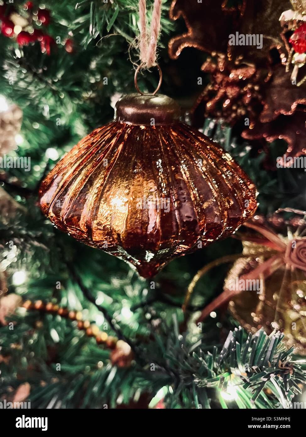 Decoraciones navideñas de bronce marrón iluminadas con luces de hadas en un árbol de Navidad Foto de stock