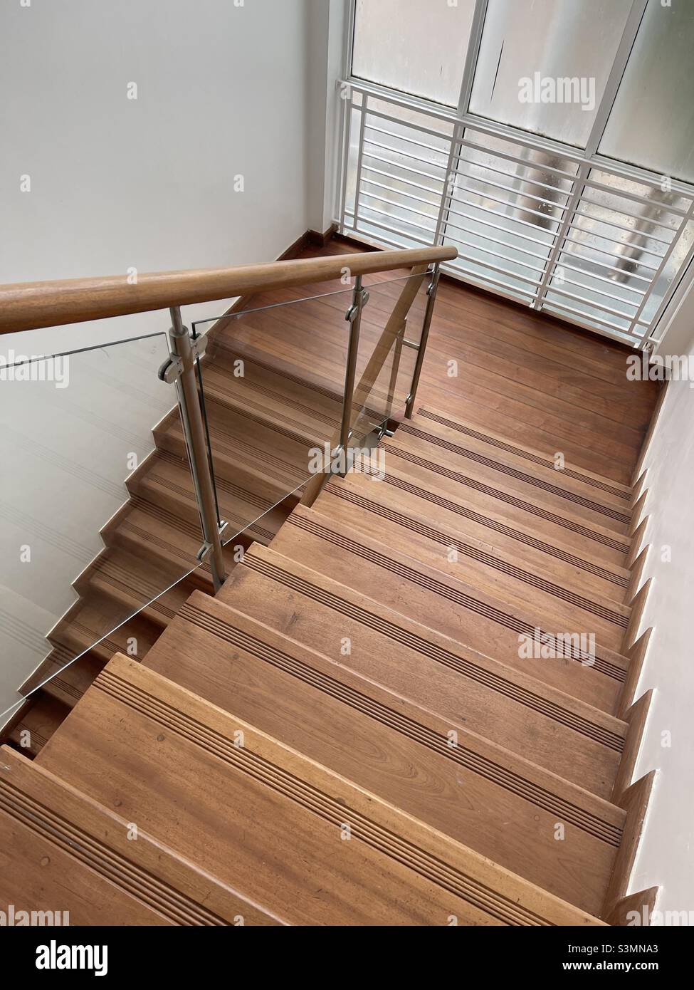 Escalera de madera contra paredes blancas Foto de stock