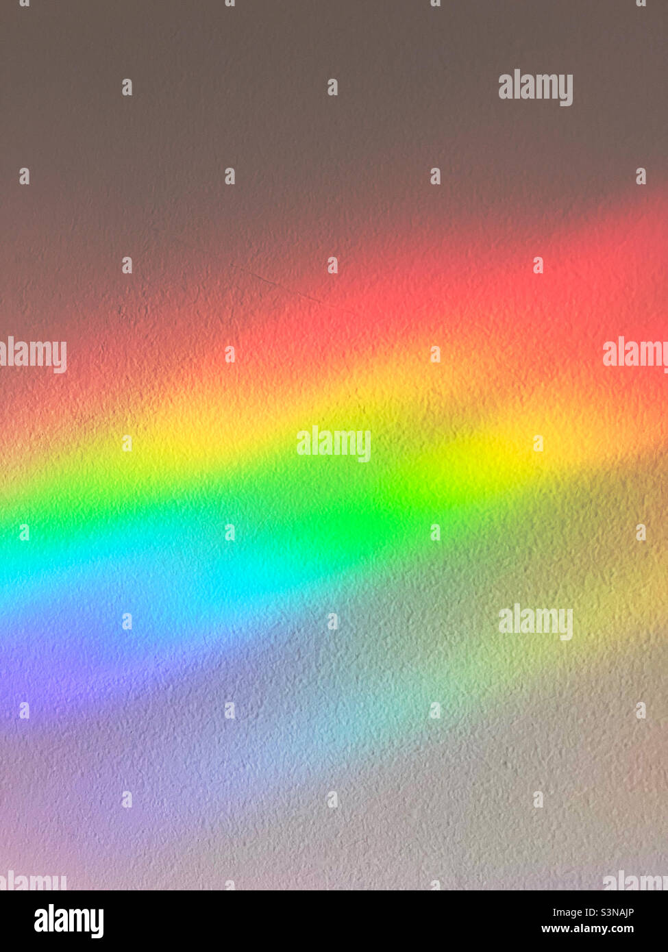 Un efecto arco iris abstracto en una pared interior. Foto de stock