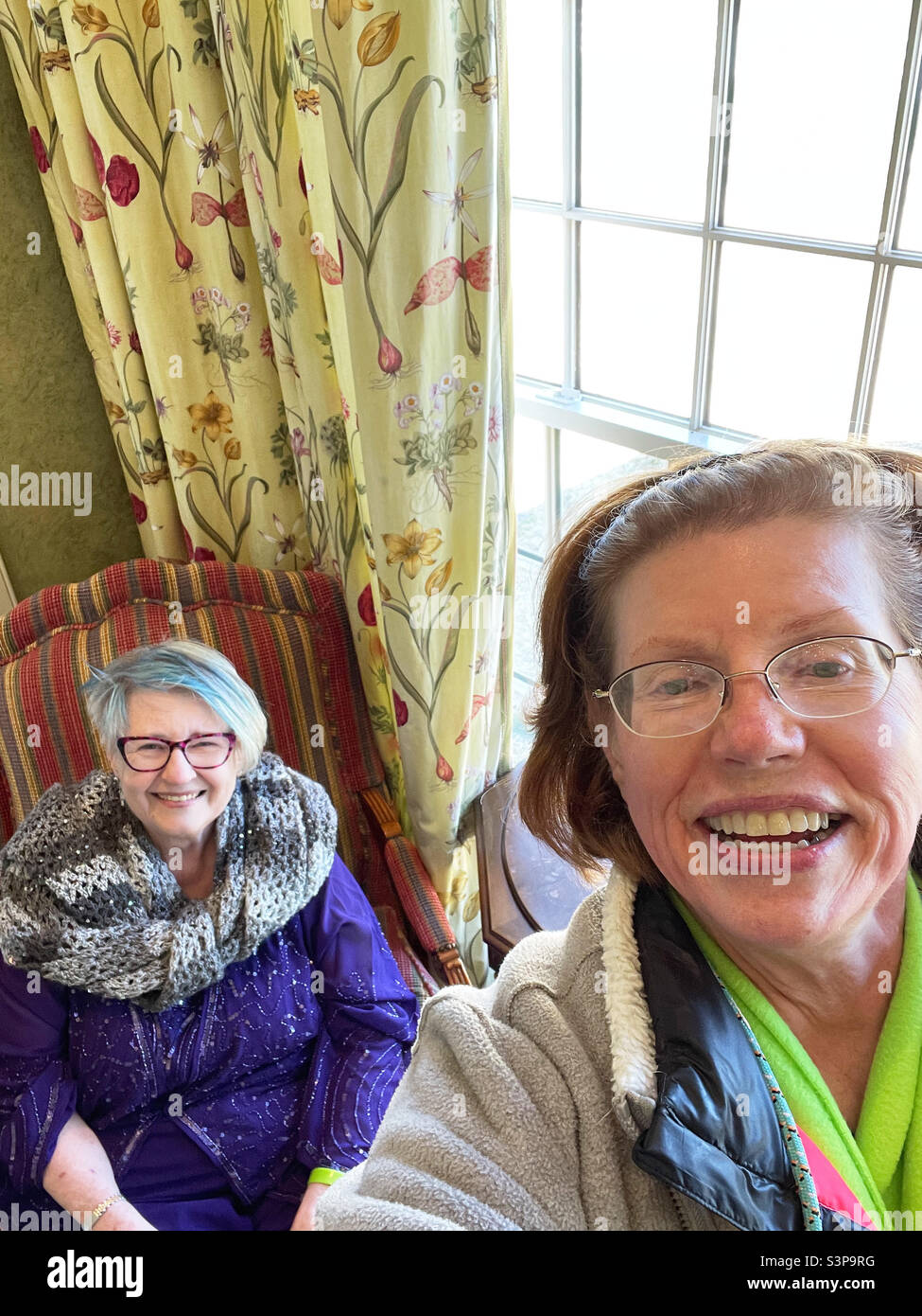 Dos personas mayores con grandes sonrisas llevando una selfie en el interior. Foto de stock