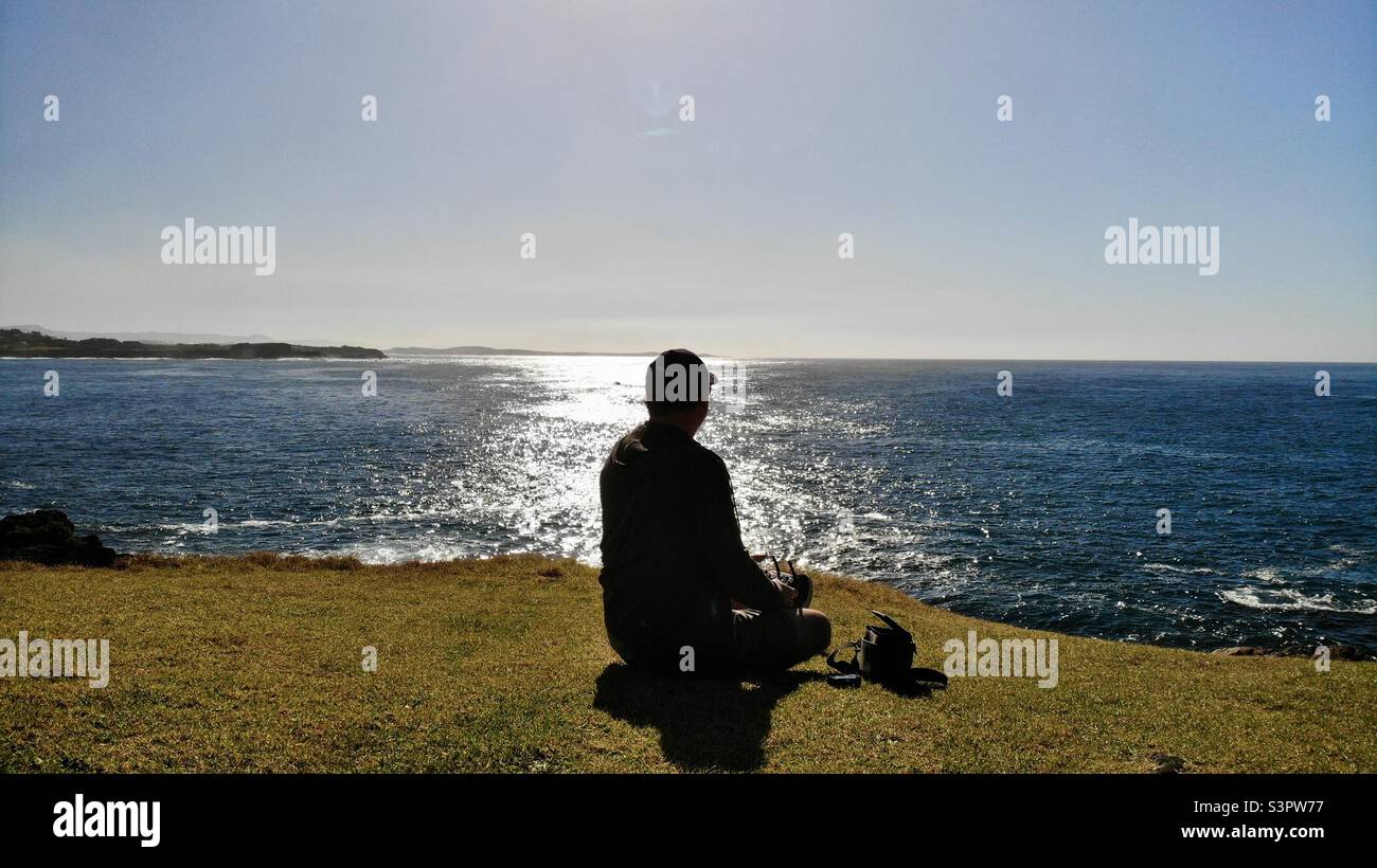 Hombre tranquilo sentado al lado del océano Foto de stock