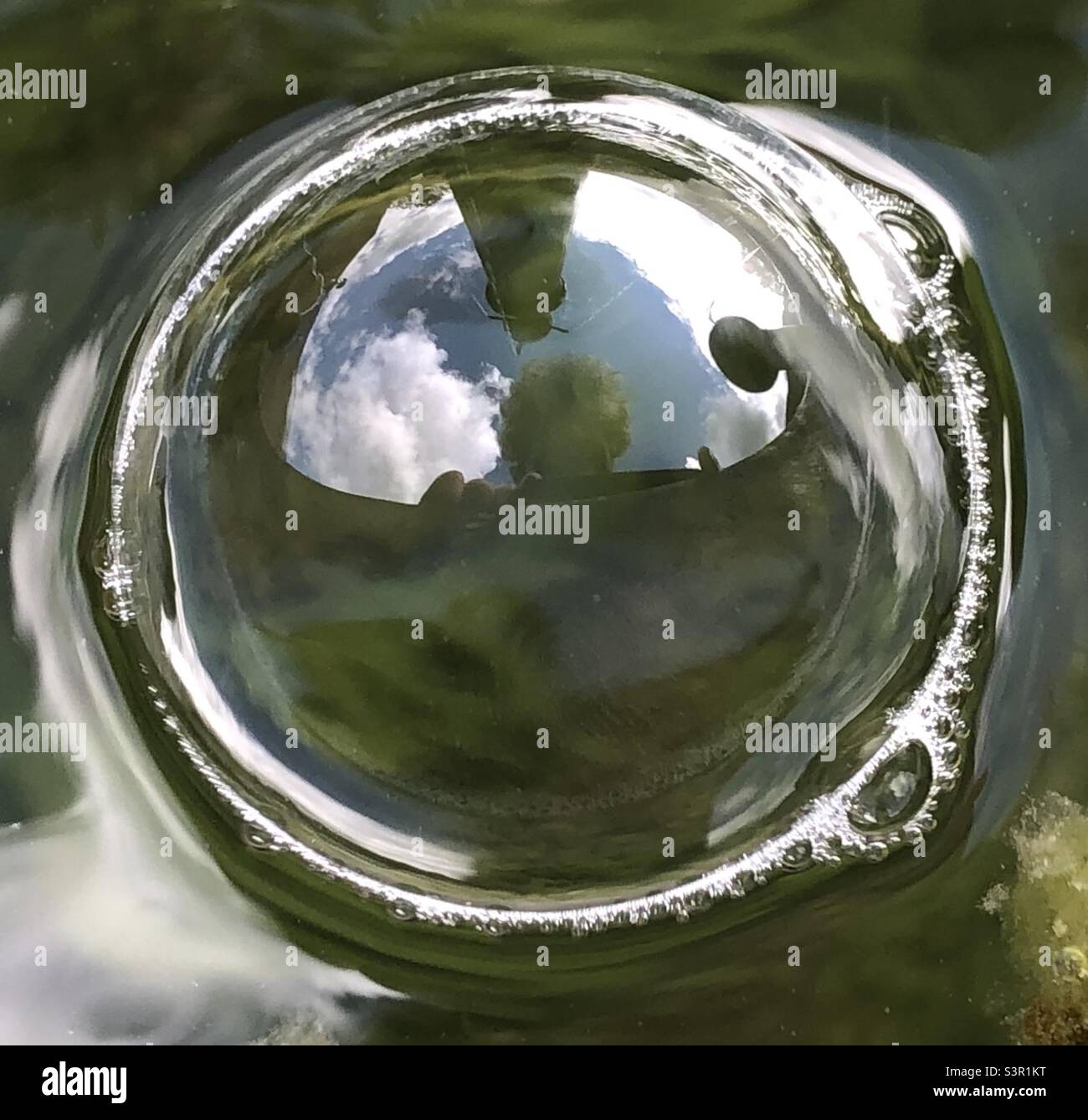 En el ojo de la burbuja. Autorretrato en una burbuja en una fuente con el cielo y la fuente reflejados arriba. Foto de stock