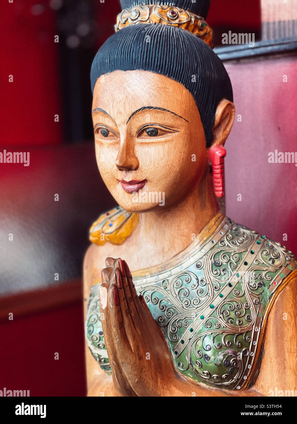 Figura de madera tallada con las manos en un gesto de bienvenida en el restaurante tailandés Foto de stock