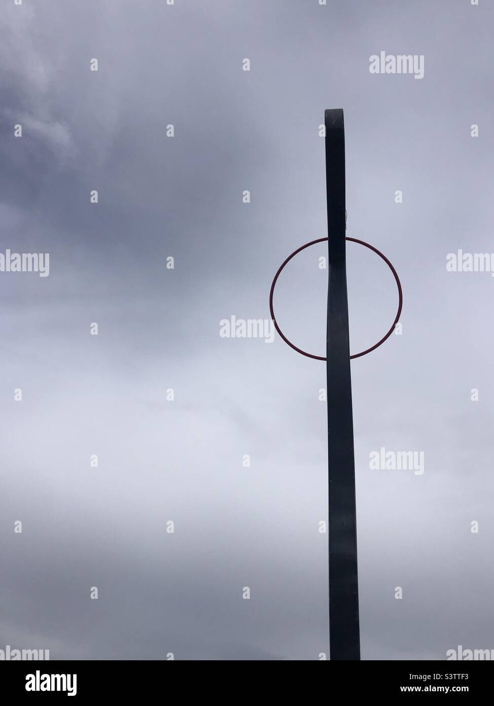 Composición minimalista de aro y barra de metal contra un cielo gris nublado Foto de stock