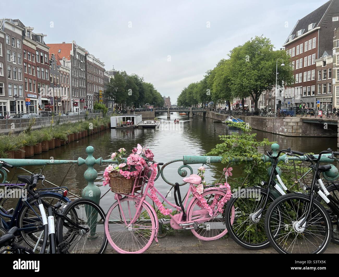 Bicicleta rosa en el puente sobre un canal de Ámsterdam Foto de stock