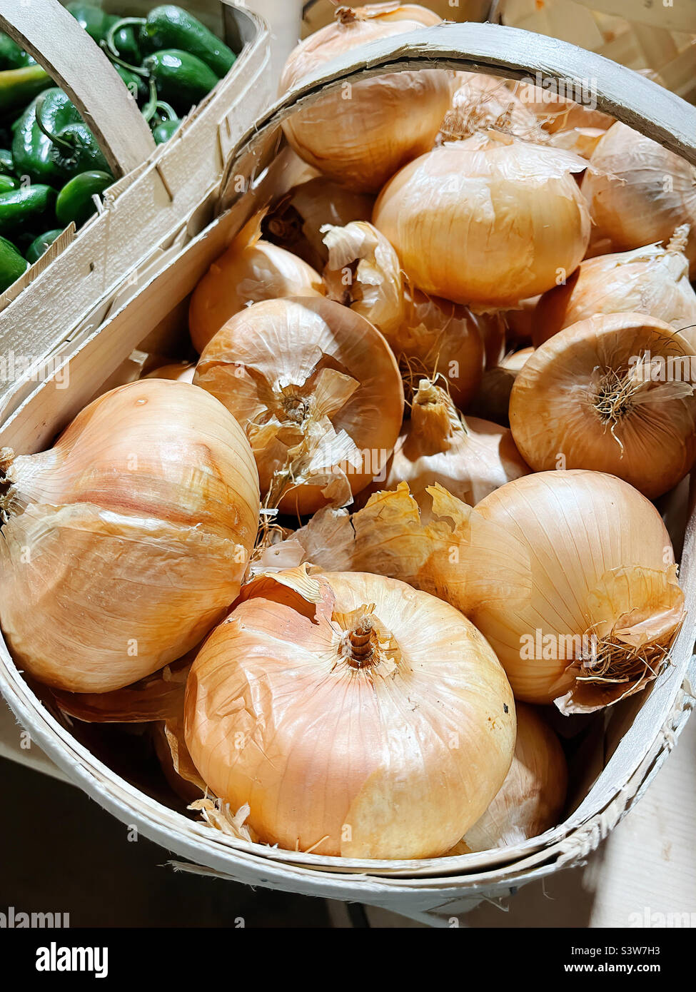 Cebollas frescas en una cesta que se venden en un mercado local de agricultores. Foto de stock