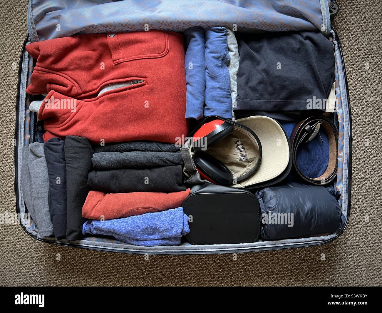 https://c8.alamy.com/compes/s3wkby/maleta-bien-equipada-con-varias-prendas-incluyendo-camisetas-capas-de-abrigo-y-protectores-auditivos-lista-para-viajar-s3wkby.jpg