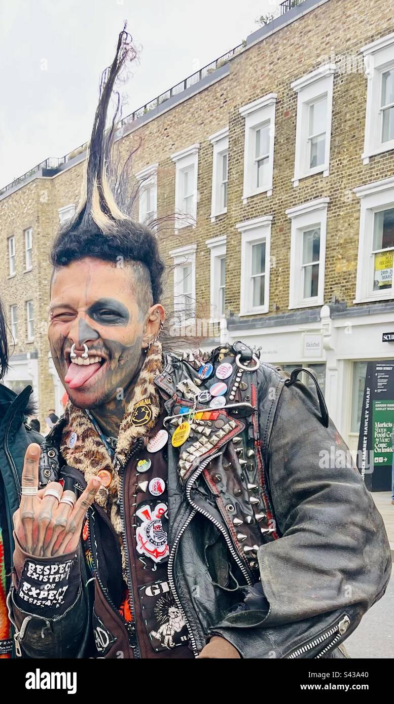 Hombre vestido con ropa Punk Rocker con pelo de punta y una guitarra posan  para fotos turísticas en Camden High Street, Camden, Londres, Reino Unido  Fotografía de stock - Alamy