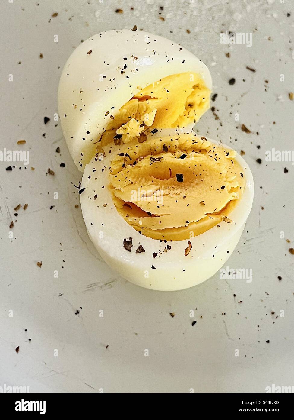 Huevo duro cortado por la mitad con pimienta molida Foto de stock