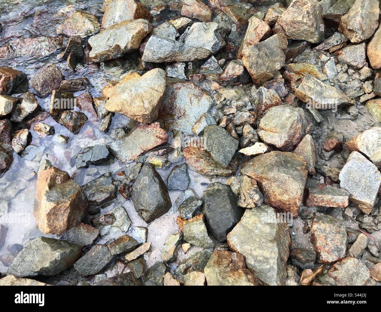 Rocas en la playa coloridas medio sumergidas en la marea Foto de stock