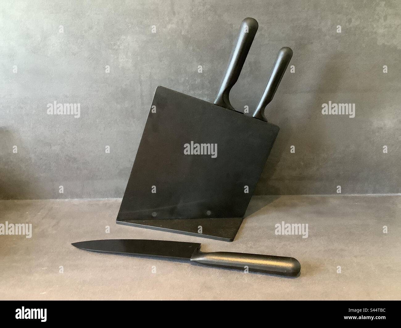 Elegante bloque de cuchillo negro y pared de hormigón en la cocina Foto de stock
