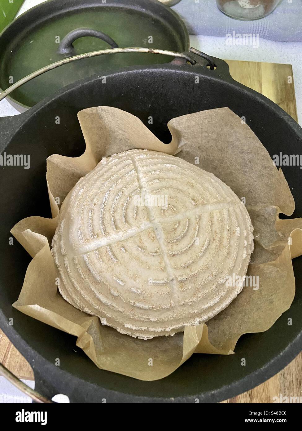 Proceso de fabricación de pan de masa madre - la masa ranurada se coloca en el horno holandés caliente listo para ser horneado Foto de stock