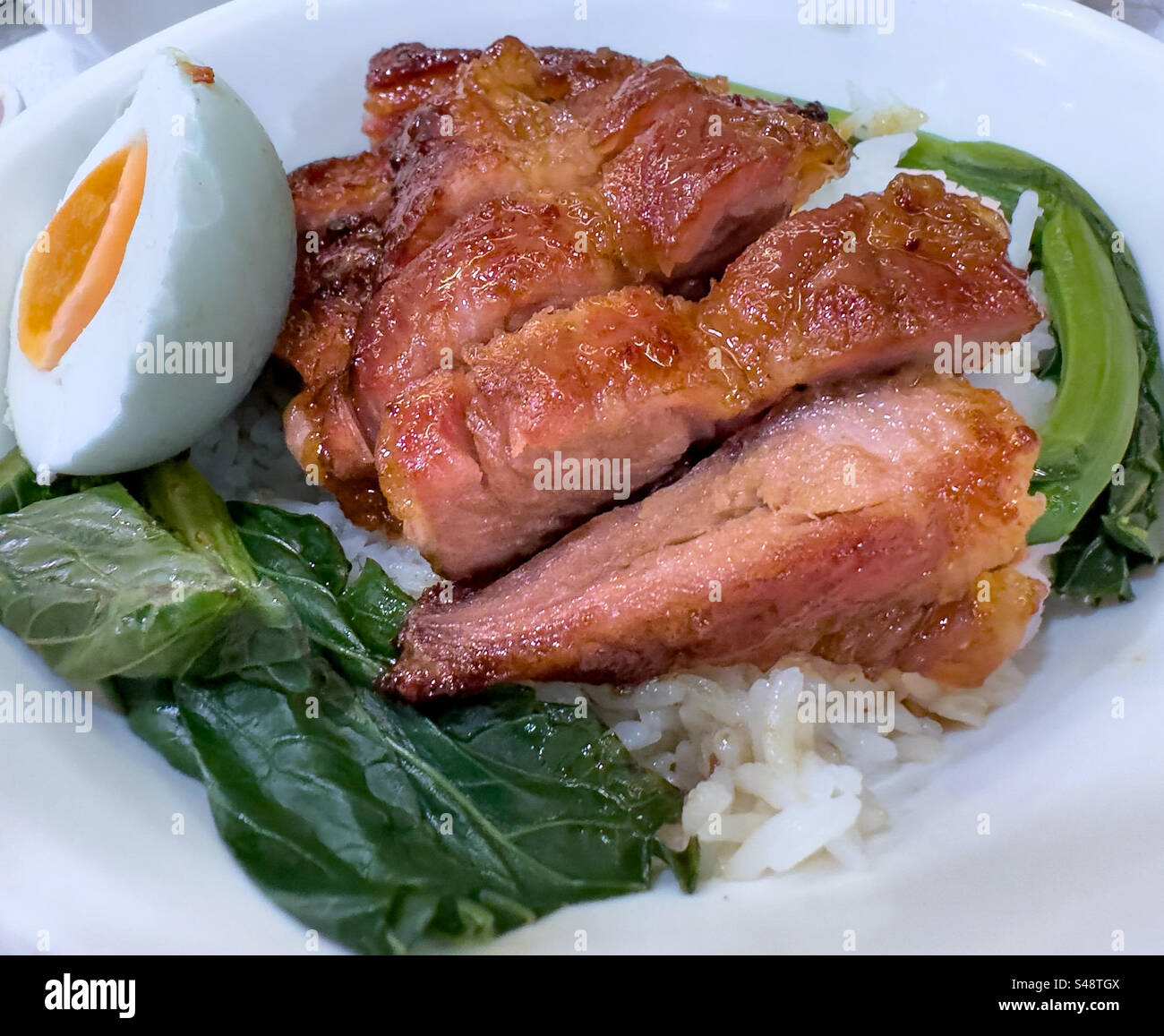 Plato de cerdo barbacoa chino (char sui) en cama de arroz con huevo duro Foto de stock