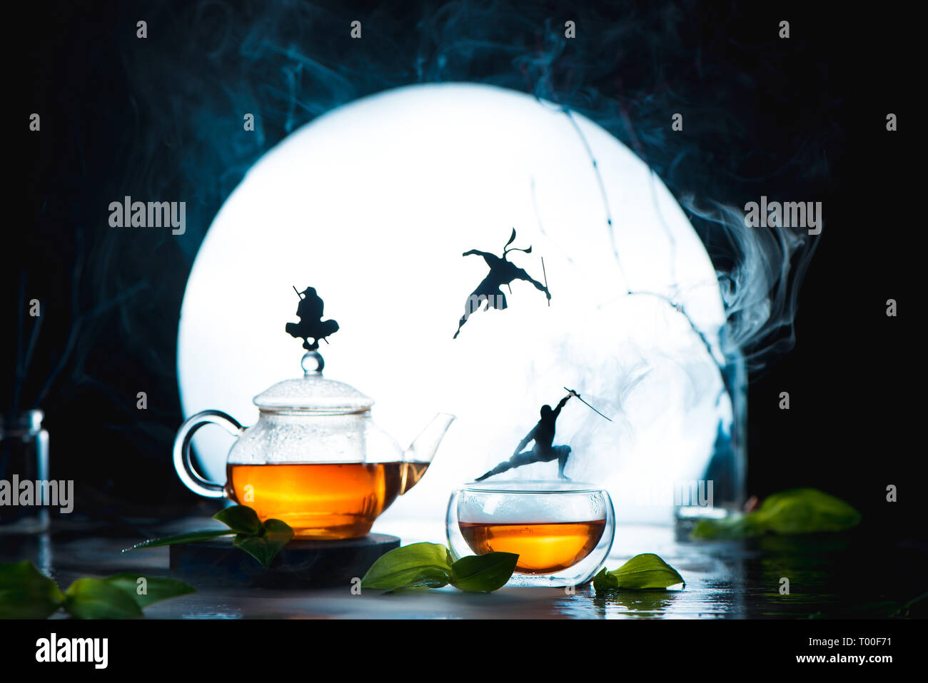 Fotografía TÉ conceptual con ninja siluetas en tazas de té. Bebida caliente creativo encabezado con luna llena y espacio de copia Foto de stock