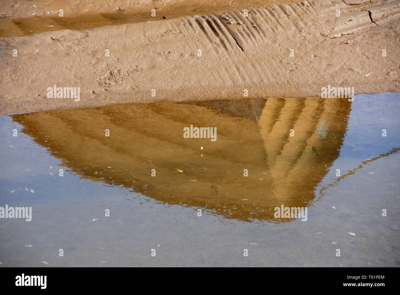 La reflexión de proa del pequeño barco varado en la piscina a la izquierda en la marea baja. Staithe Brancaster, Norfolk, Inglaterra Foto de stock