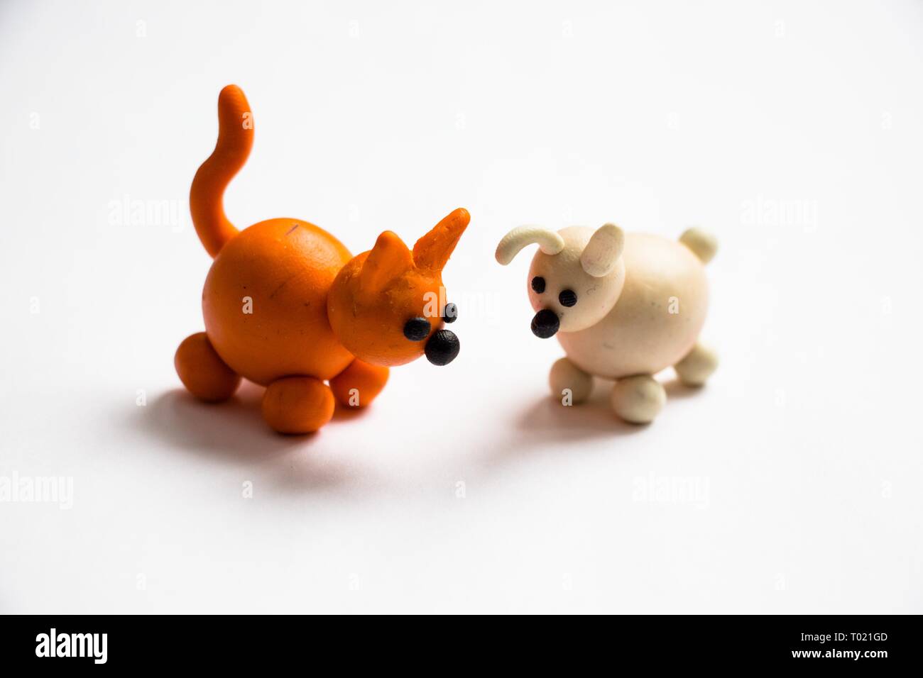 Dos pequeños perros de color naranja y blanco sobre un fondo de luz hechas de plastilina. Son muy buenos y simpáticos animales. Foto de stock