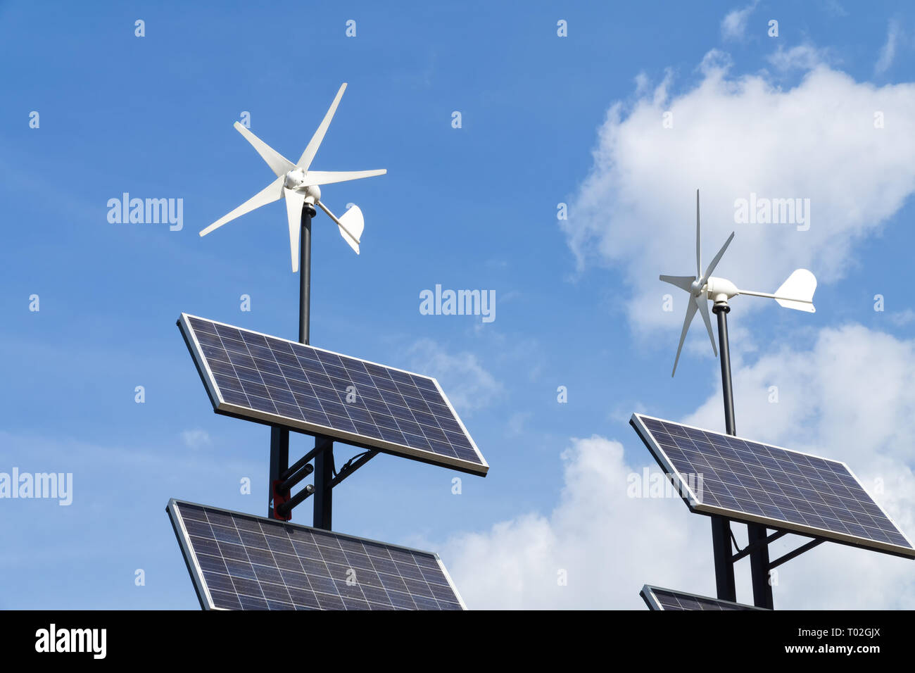 Pequeños generadores de energía eólica y conjunto de paneles solares contra  el cielo azul con nubes blancas. Concepto de energía renovable Fotografía  de stock - Alamy