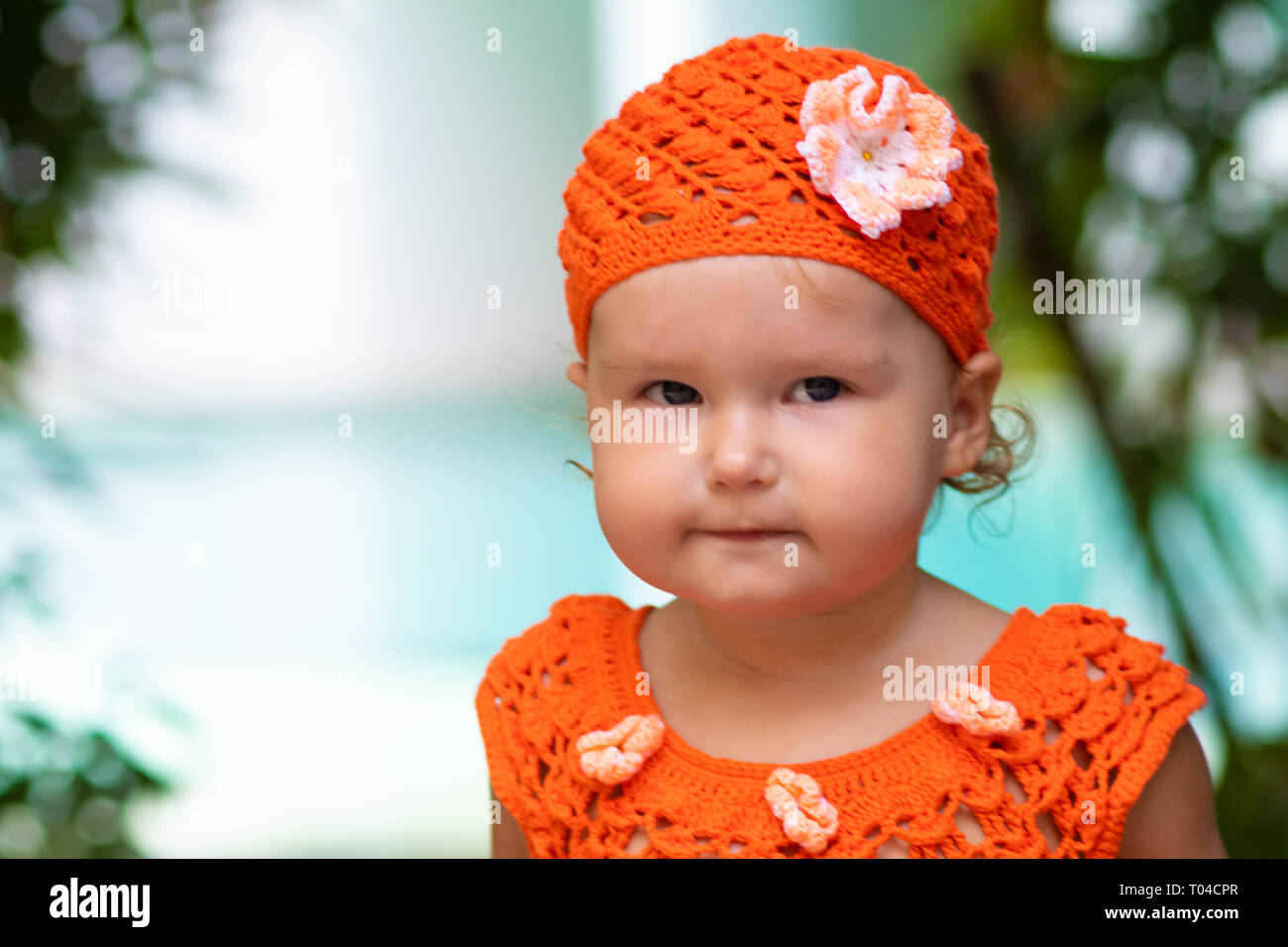 Una chica en un vestido tejido de color naranja y sombrero se sorprende, se  regocija, gritos, llantos, levanta sus manos. los niños del concepto de  moda Fotografía de stock - Alamy