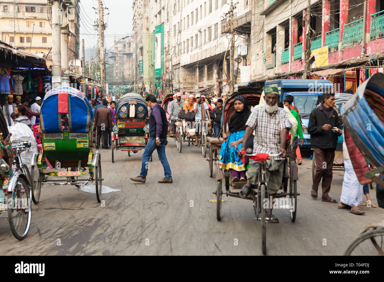Llenado de una calle muy transitada en el centro de la ciudad de Dhaka. Rickshaws, autobuses, coches y personas compiten por un espacio en la calle llena de gente. Foto de stock