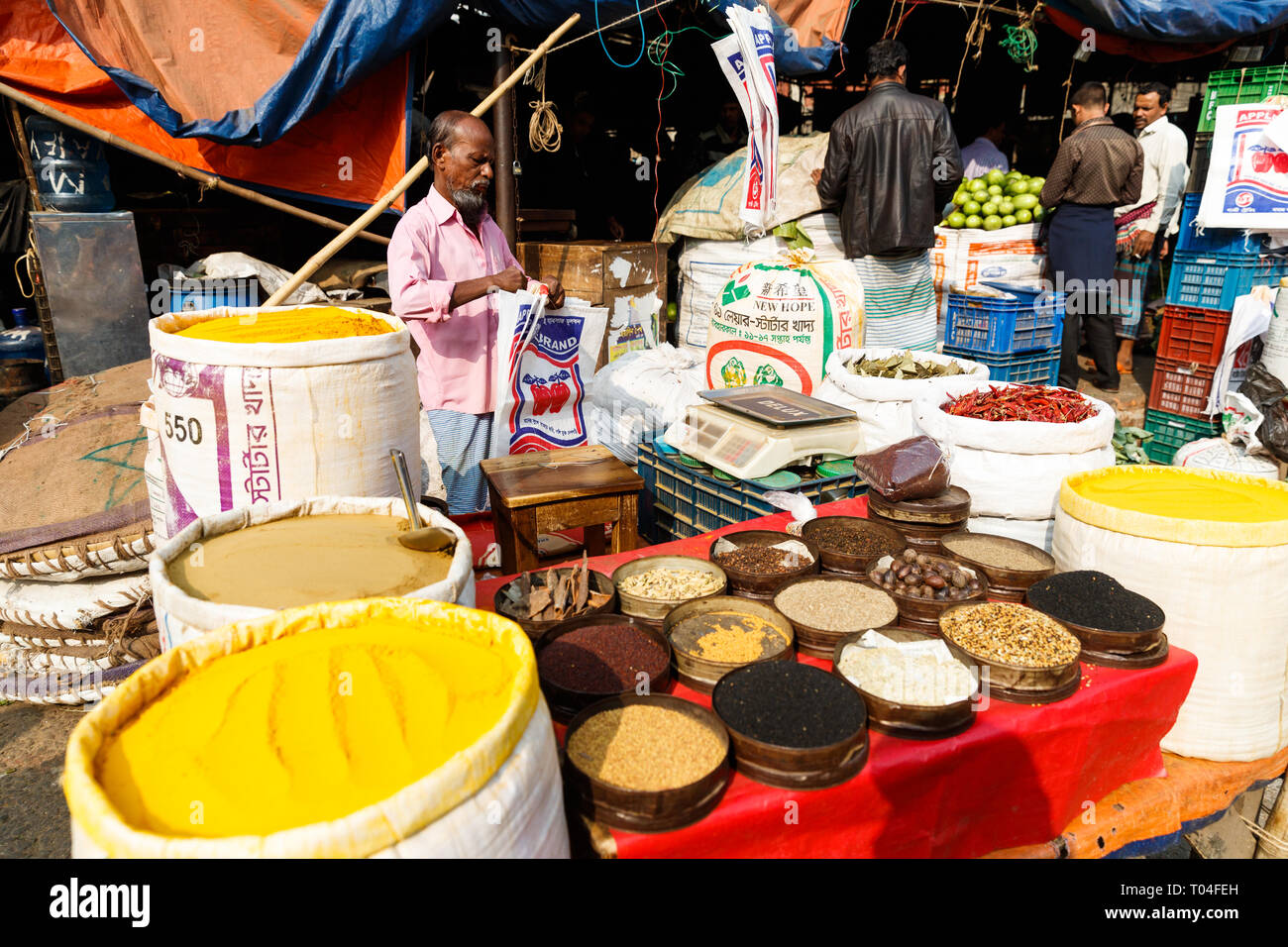 Colorido Mercado de frutas y especias con proveedores comerciales y personas que transportan mercancías en las calles de Dhaka, Bangladesh Foto de stock