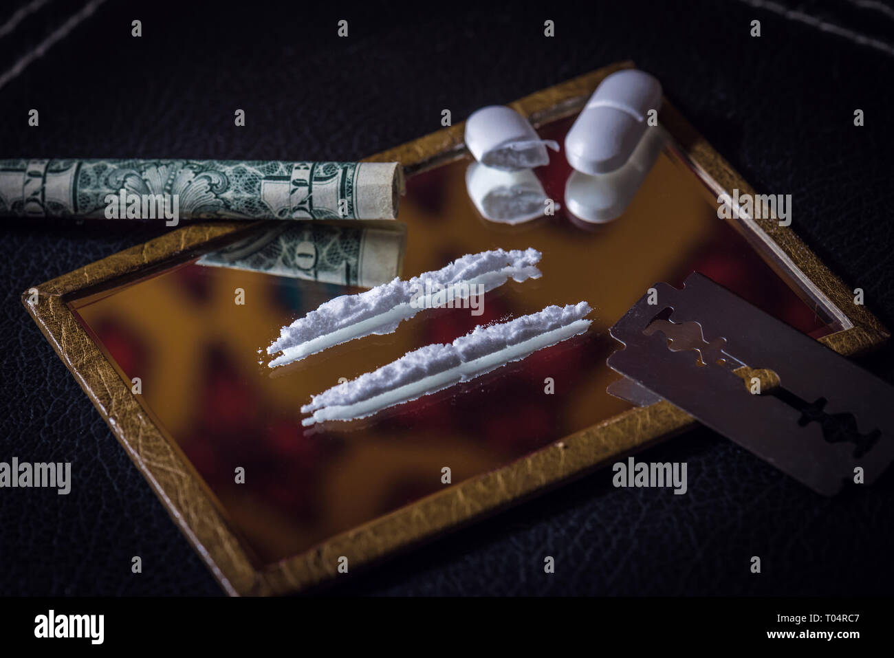 Imagen conceptual del uso indebido de drogas con dos líneas en un espejo y una media pastilla picada Foto de stock