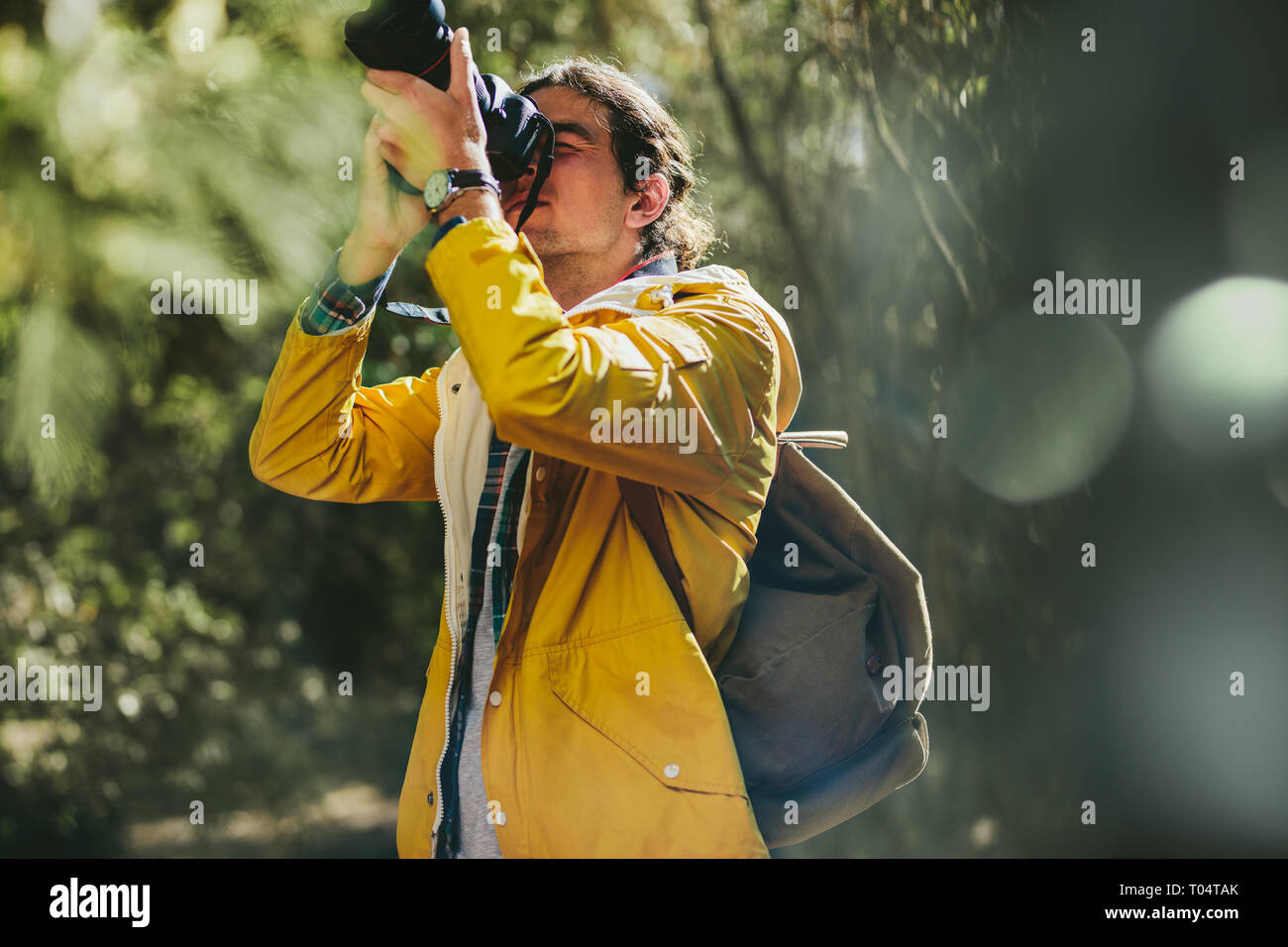 Retrato de un explorador para tomar fotos de la naturaleza de pie en un bosque. El fotógrafo llevaba chaqueta y mochila haciendo fotografía de naturaleza. Foto de stock