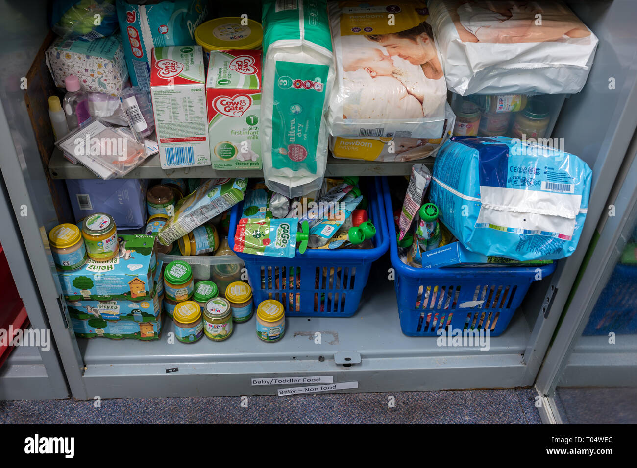 Los estantes de almacenamiento en una iglesia local de confianza Trussell UK Food Bank warehouse mostrando los alimentos para bebés, artículos de tocador, leche y pañales listo para paquetes de alimentos Foto de stock