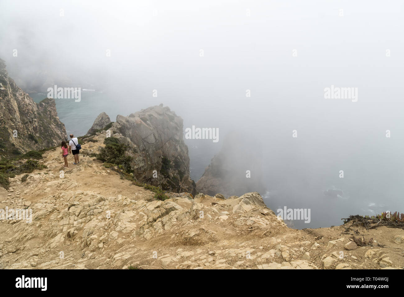CABO DA ROCA, Portugal - 2 de septiembre de 2018: Los turistas de cabo Roca acantilados en la niebla. Las rocas están oscurecidas por las nubes o la niebla. Cabo Roca más occidental es par Foto de stock